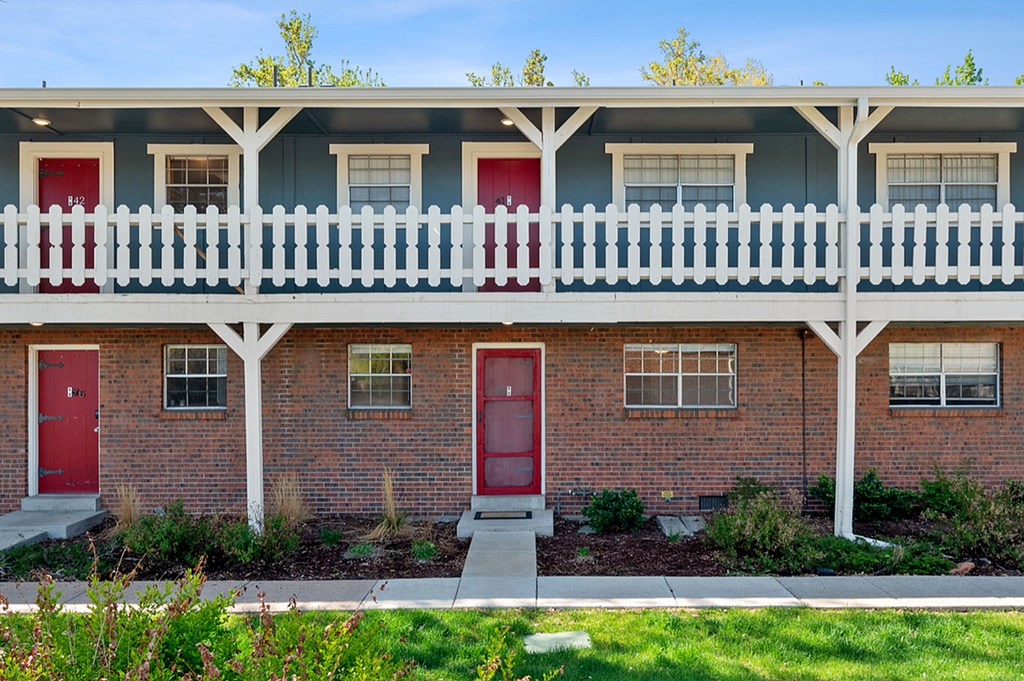 A row of red doors with white window frames and a white fence.