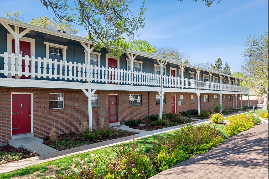 A row of houses with red doors and white fences.