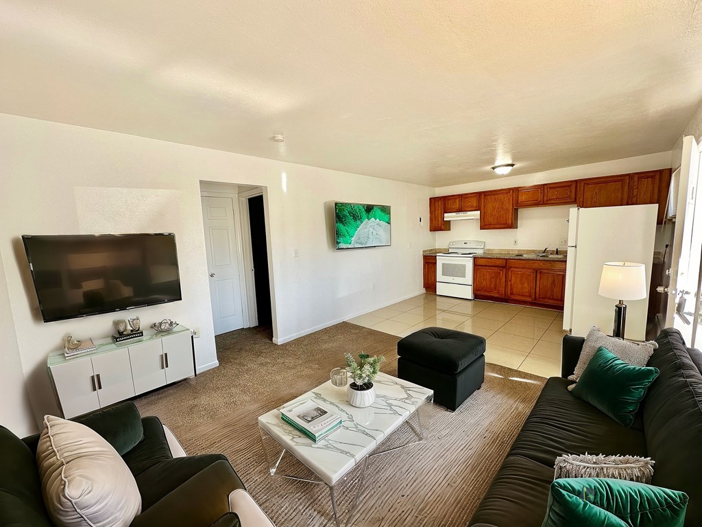 A living room with a black couch, a white coffee table, and a flat screen TV.
