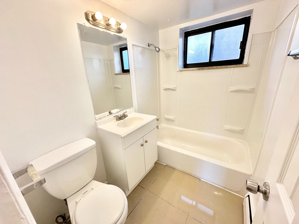 A white bathroom with a toilet, sink, and bathtub.