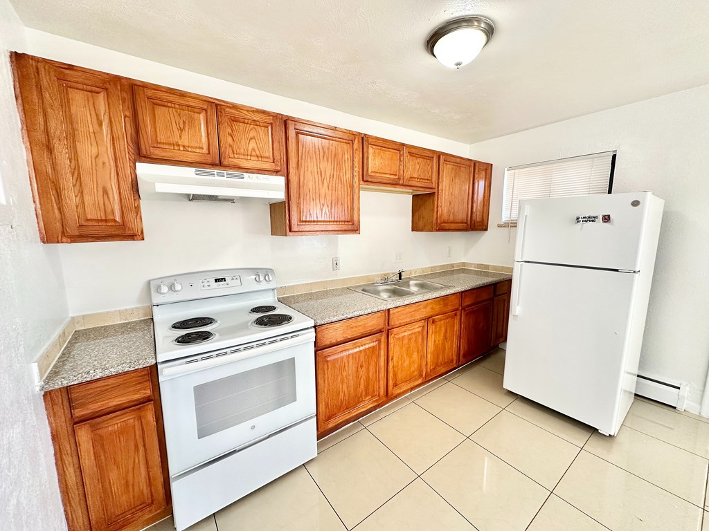A kitchen with white appliances and wooden cabinets.