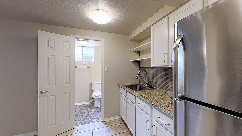 A kitchen with a stainless steel refrigerator and white cabinets.