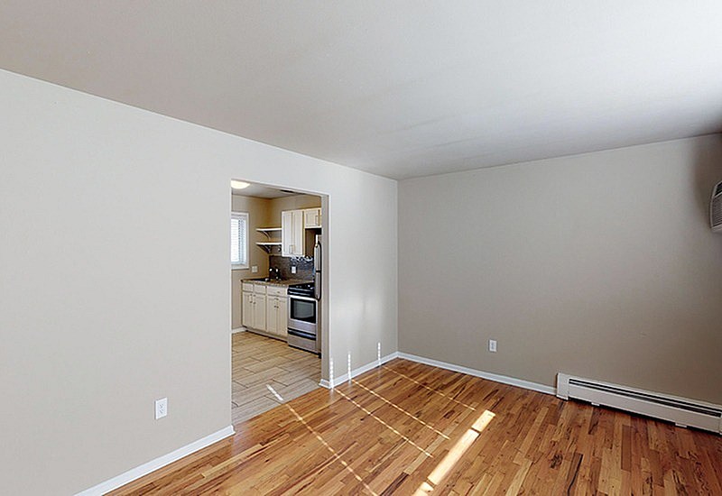 A room with wooden floors and a view of a kitchen.