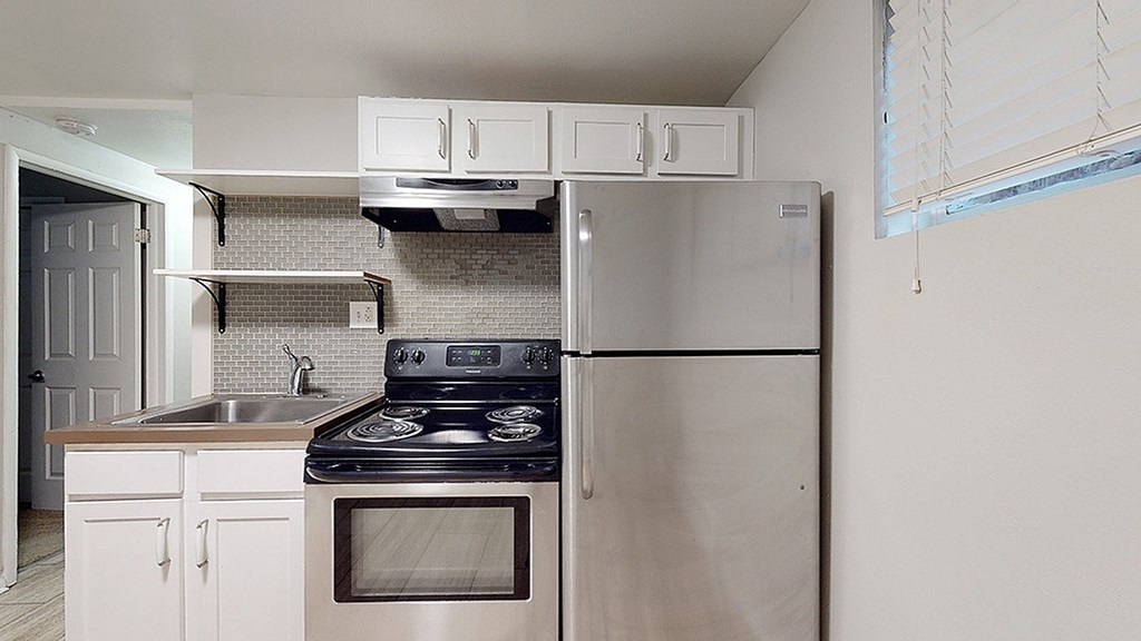 A kitchen with a stove, sink, and refrigerator.