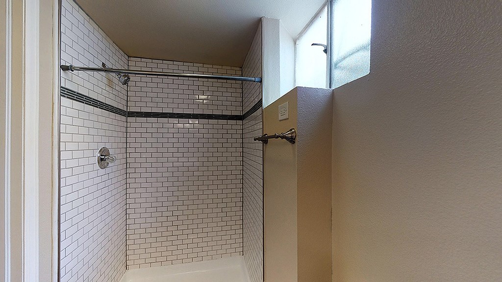A bathroom with a tiled shower and a white door.