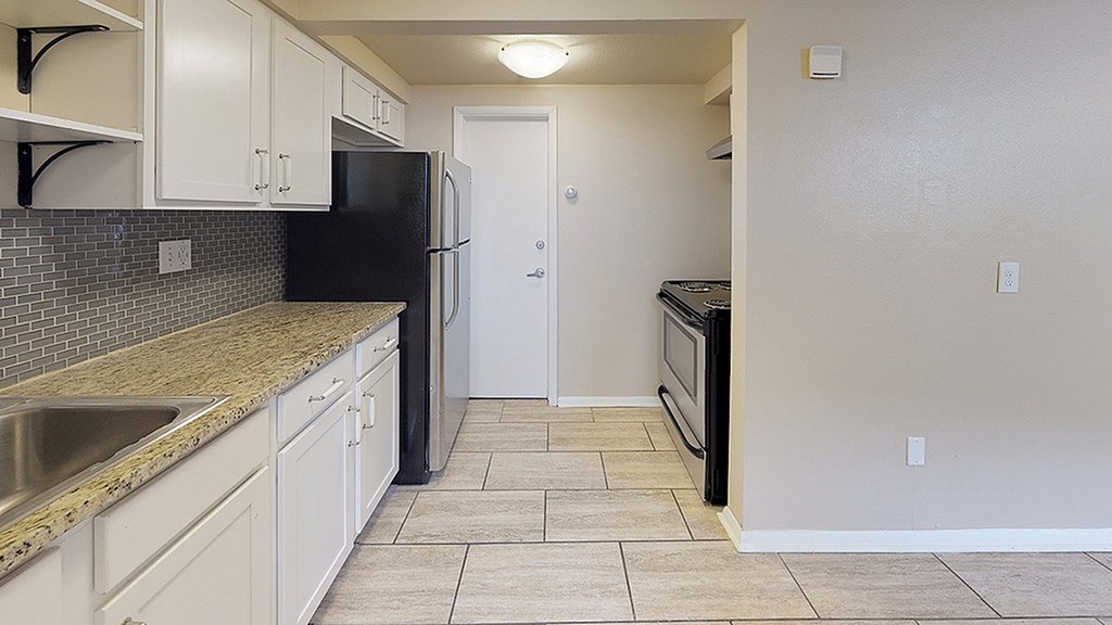 A kitchen with a black fridge and white cabinets.