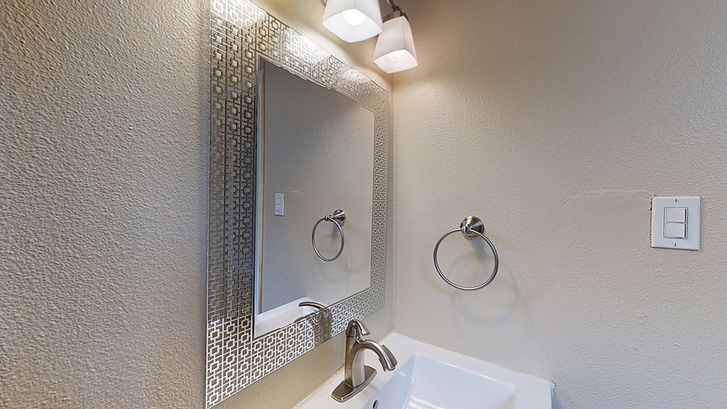 A bathroom with a white sink and a mirror above it.