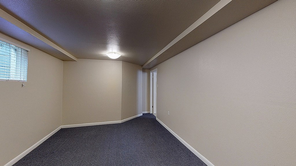 A room with a carpeted floor and a door on the right side.
