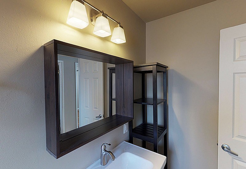 A bathroom with a sink, mirror, and shelves.