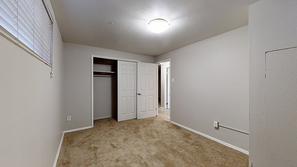 A room with a white door and a window with blinds.