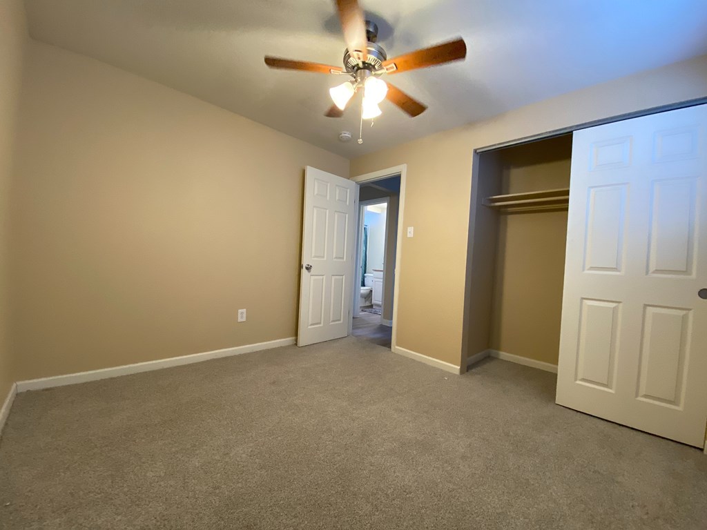 A room with a ceiling fan and two doors.