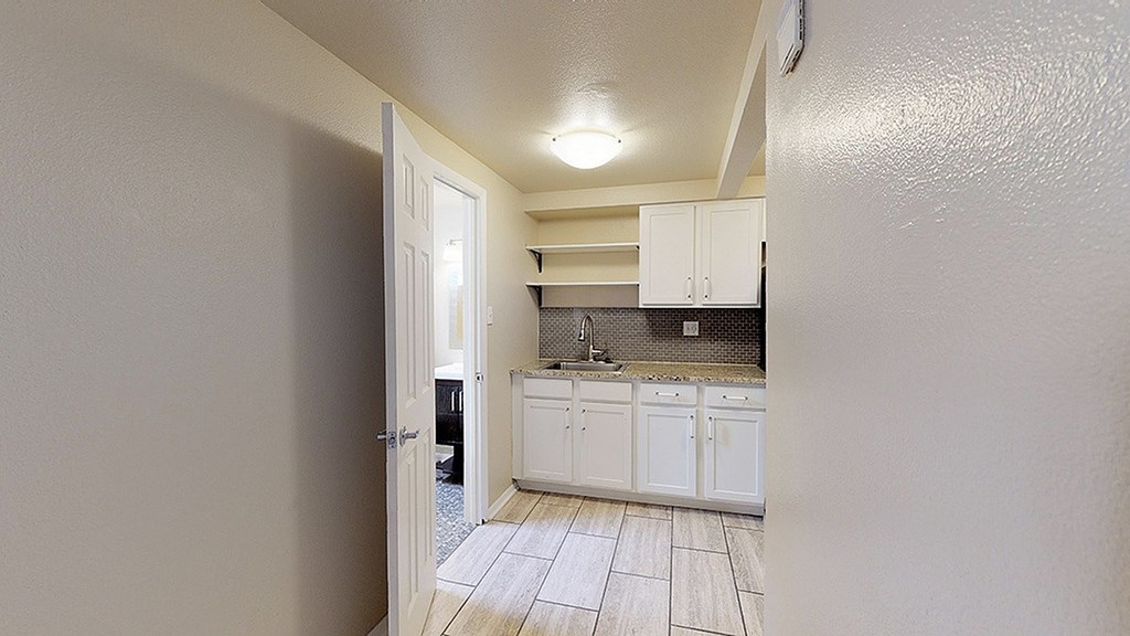 A kitchen with white cabinets and a tile floor.
