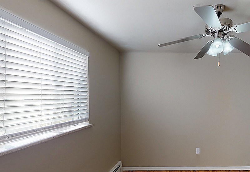 A room with a ceiling fan and a window with blinds.