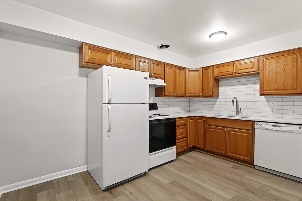 A kitchen with wooden cabinets and white appliances.