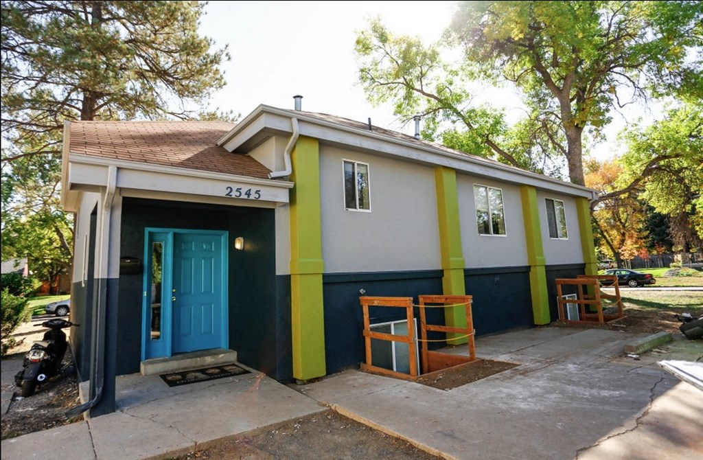A small house with a blue door and a yellow stripe on the side.