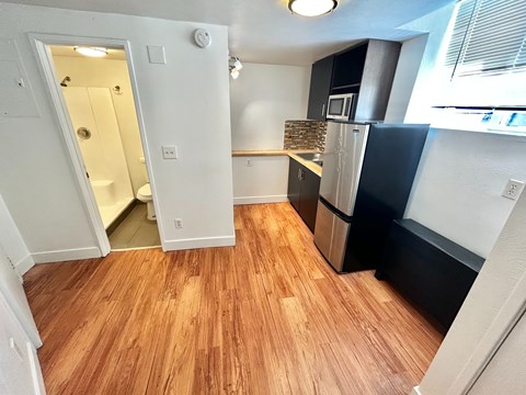 A kitchen with a refrigerator, microwave, and wooden floors.