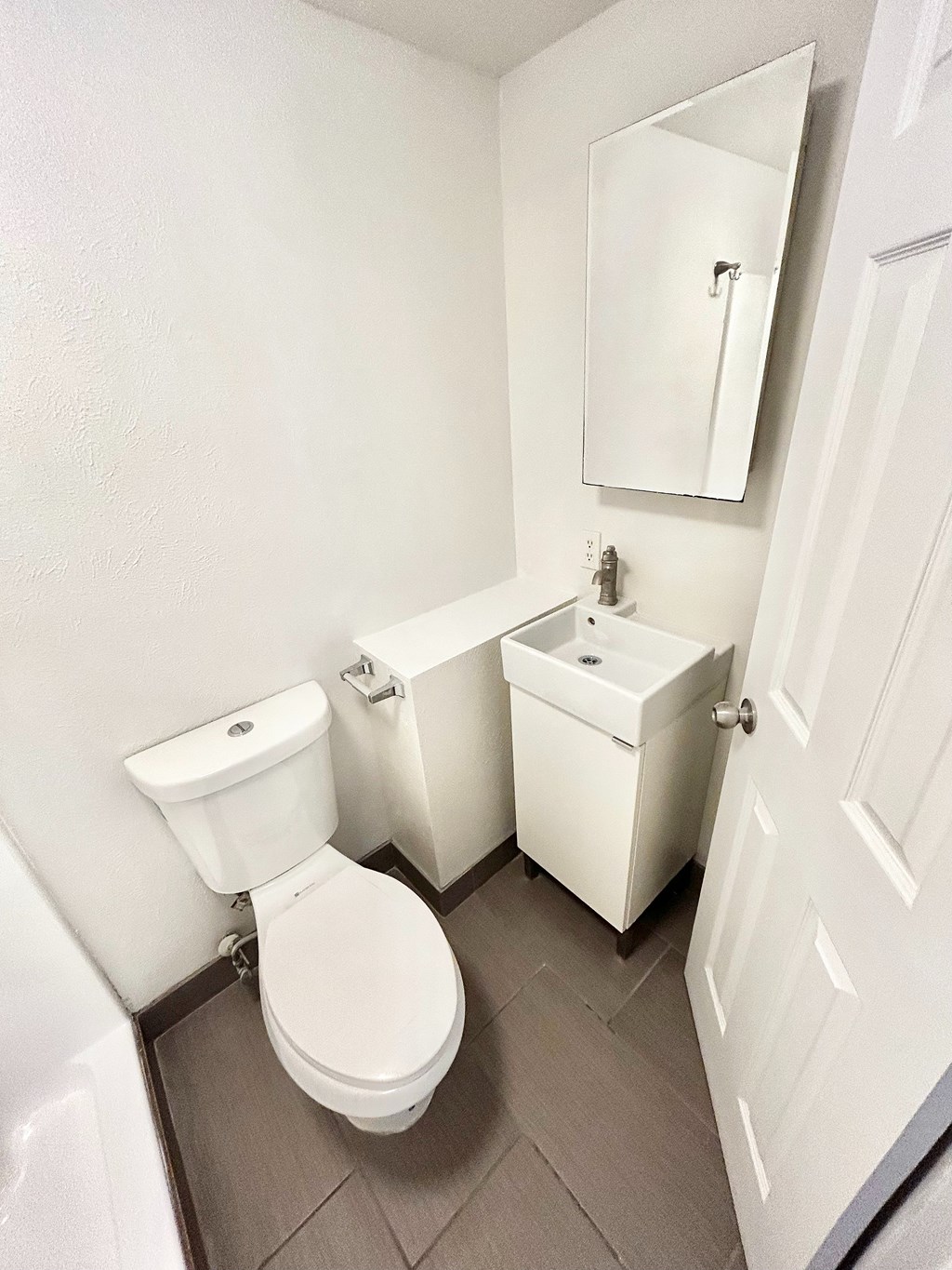 A white toilet sits next to a sink in a small bathroom.