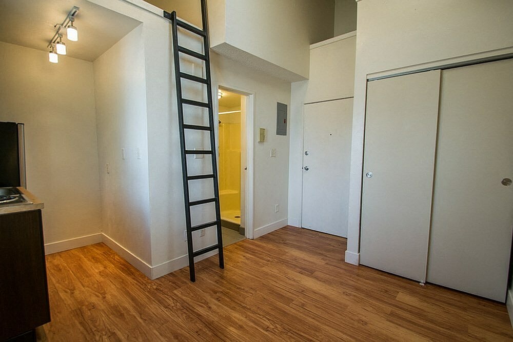 A room with a wooden floor and a ladder.