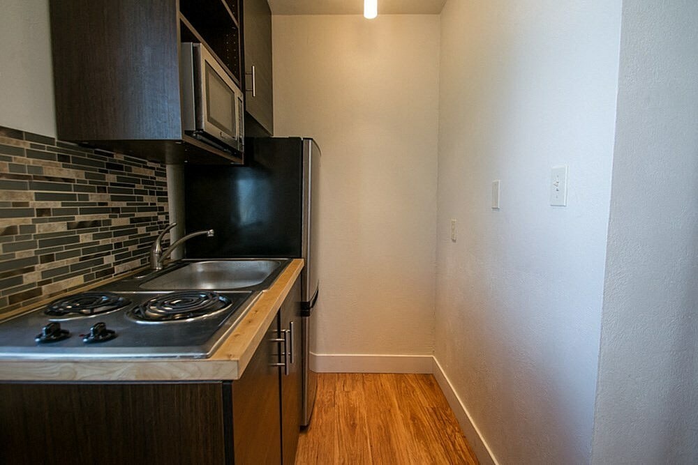 A kitchen with a black refrigerator and a stove top oven.