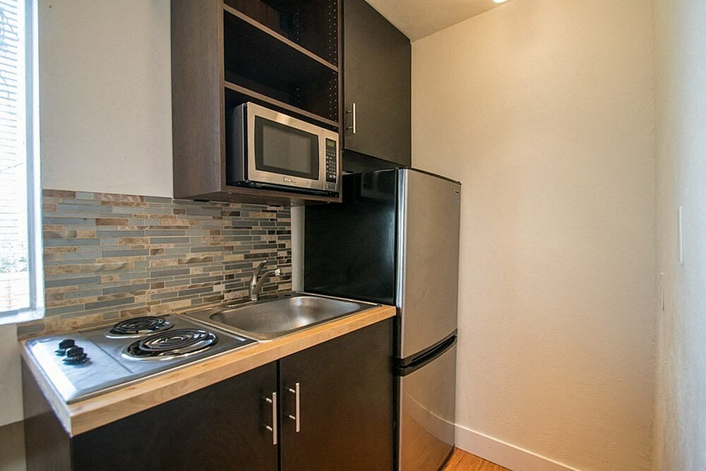 A kitchen with a black refrigerator and a stove top oven.