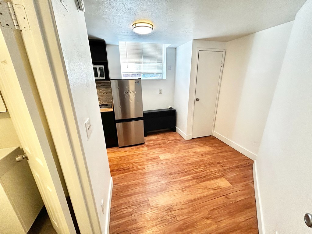 A kitchen with a white fridge and wooden floors.