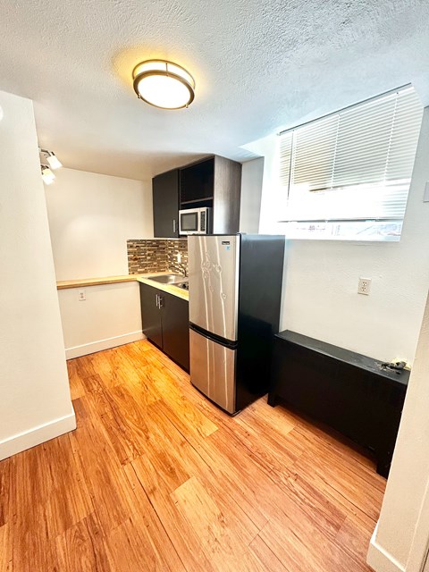 A kitchen with a black refrigerator and wooden floors.