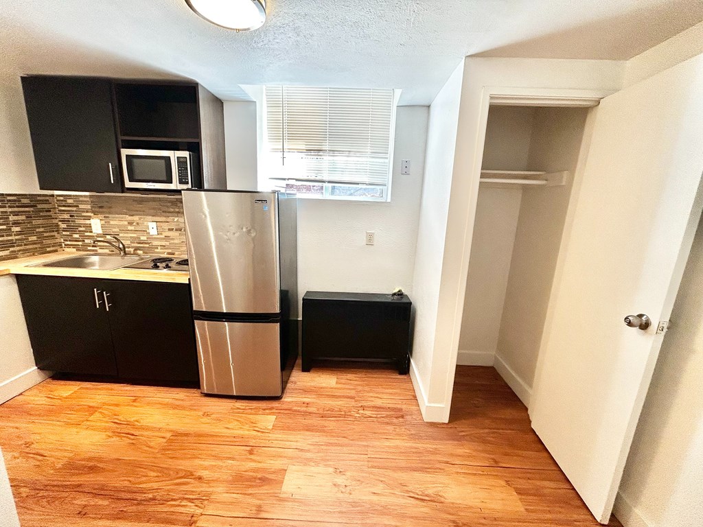 A kitchen with a refrigerator, microwave, and sink.