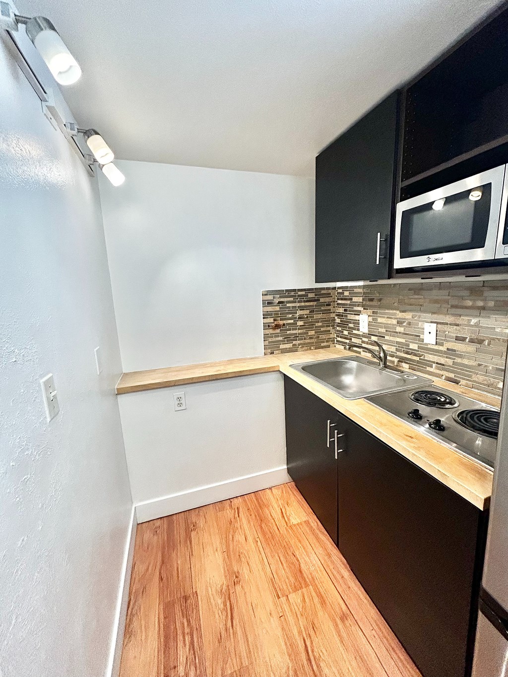 A kitchen with a wooden floor and a white wall.