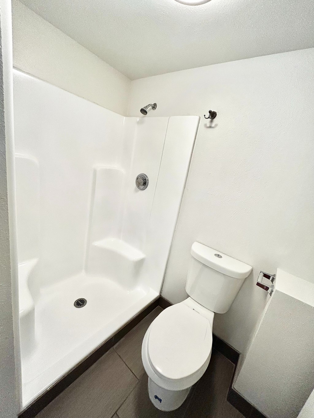 A white toilet in a small bathroom with a walk-in shower.
