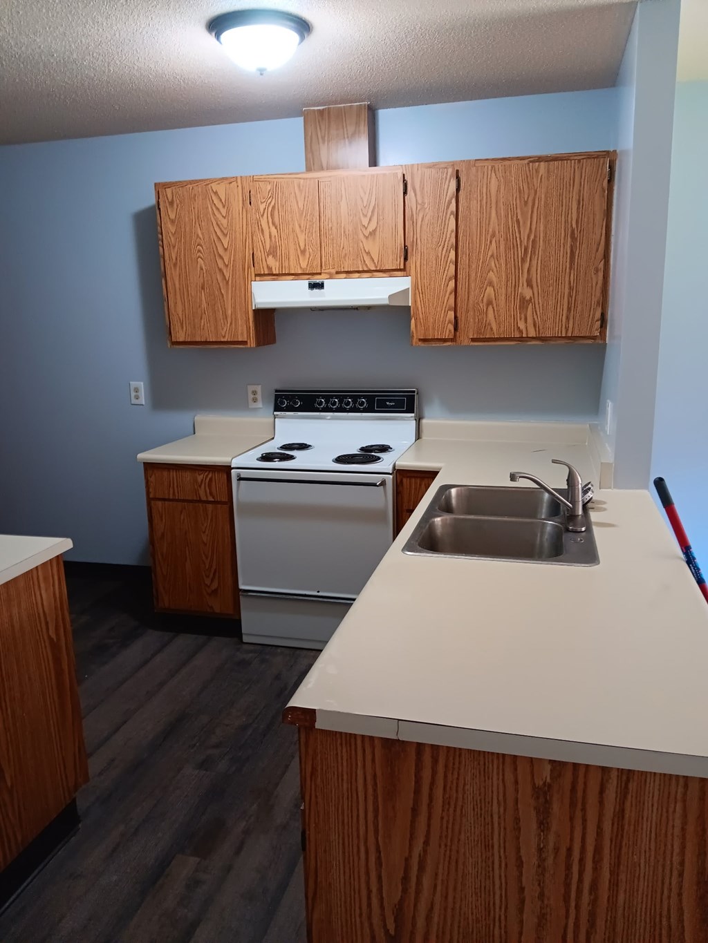 A kitchen with a stove, sink, and cabinets.