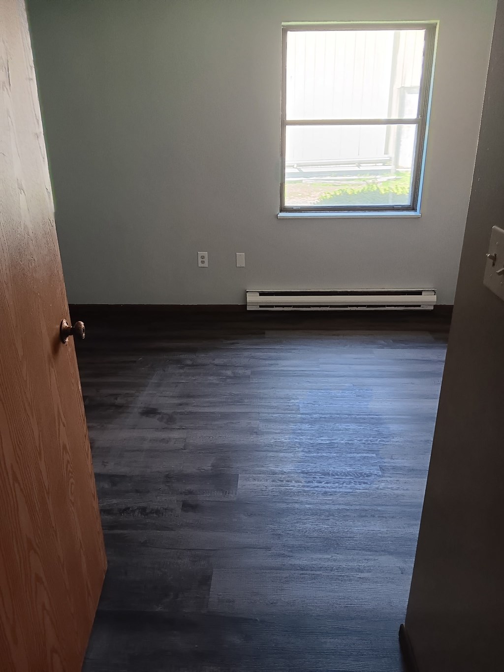 A room with a window and a wooden floor.