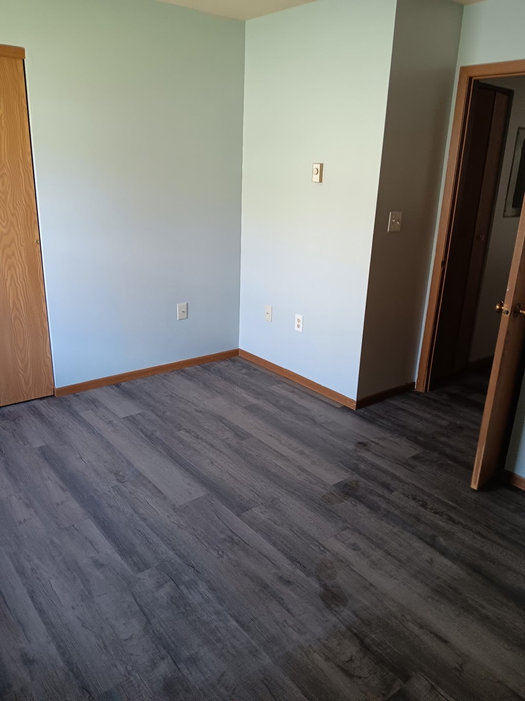A room with a grey floor and a brown door.