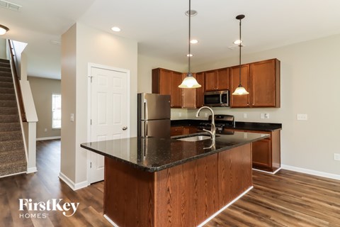 A kitchen with a black counter top and wooden cabinets.