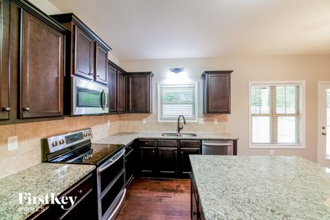 A kitchen with dark wood cabinets and a granite countertop.