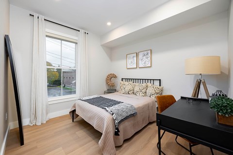 A bedroom with a bed, a desk, and a chair.