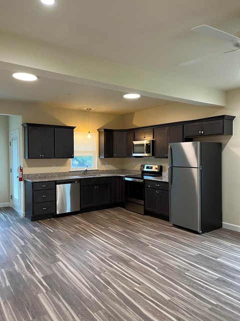 A kitchen with black cabinets and a wooden floor.