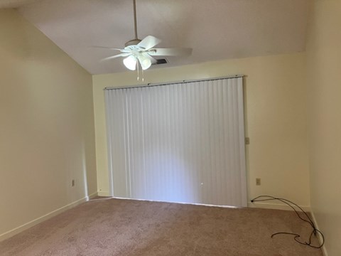 A room with a ceiling fan and a window with blinds.