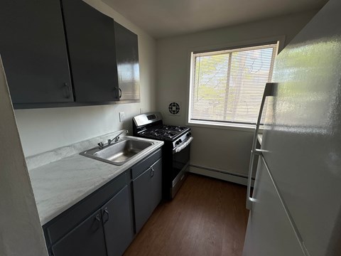 A small kitchen with a sink, stove, and refrigerator.