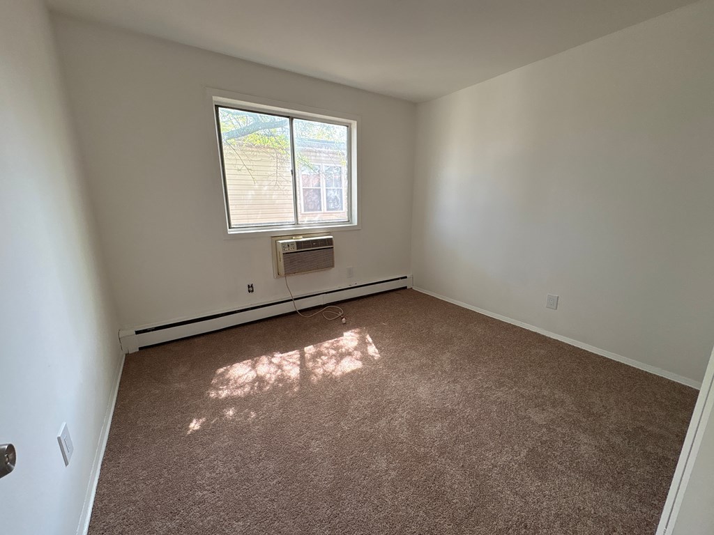 A room with a window and carpeted floor.