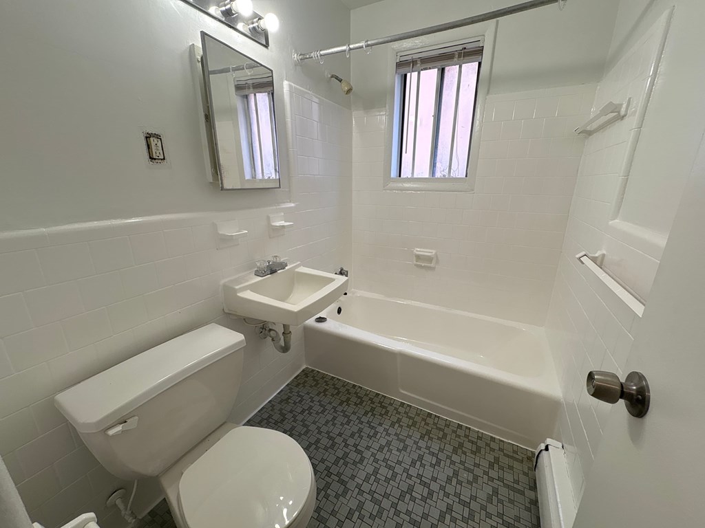 A white bathroom with a toilet, sink, and bathtub.