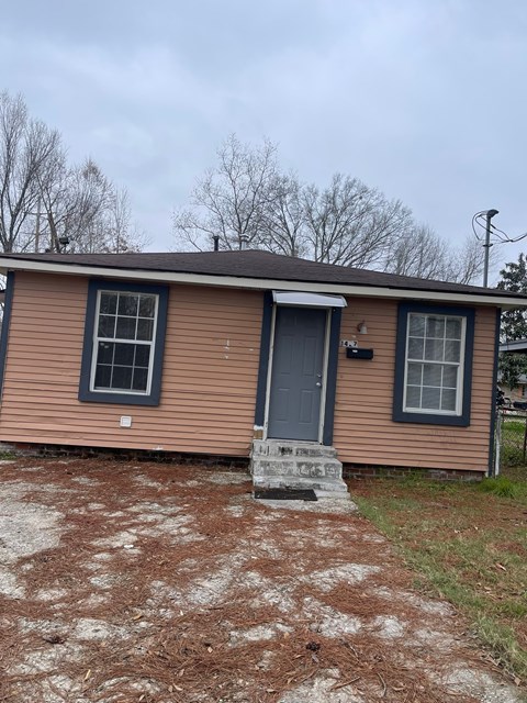 A small house with a brown siding and a grey door.