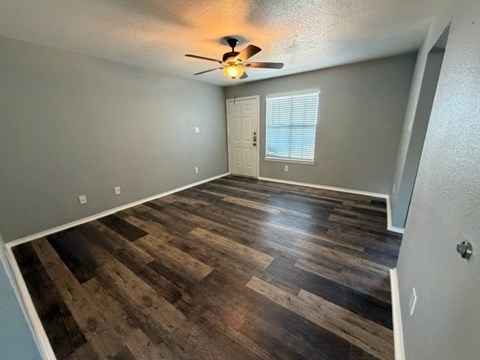 A room with a ceiling fan and wooden flooring.