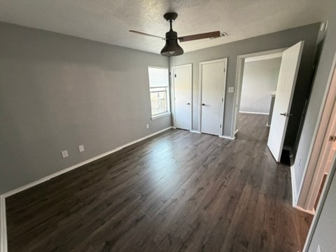 A room with wood flooring and a ceiling fan.