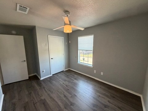 A room with a ceiling fan and a window with blinds.