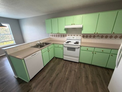 A kitchen with green cabinets and white appliances.