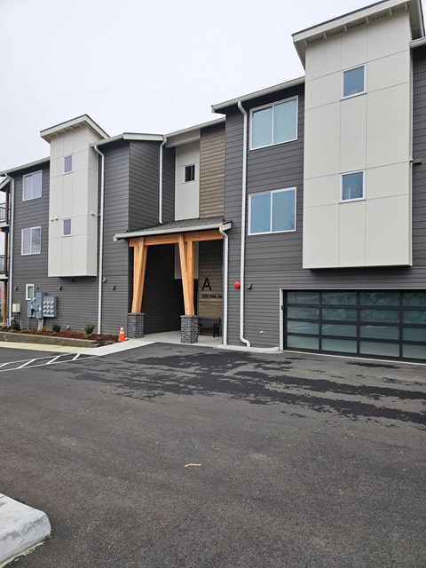 A large grey and white apartment building with a garage door open.