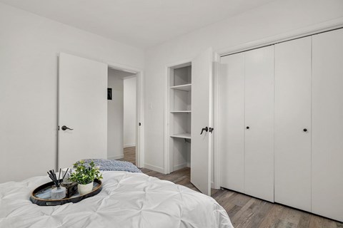 A white bedroom with a bed, a tray with plants and incense sticks on it, and a wardrobe.