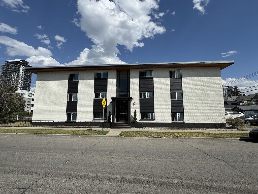 A white building with black shutters and a yellow sign on the door.