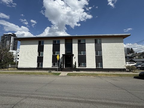 A white building with black shutters and a yellow sign on the door.