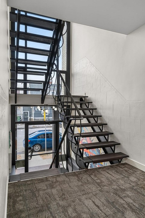 A staircase with a metal railing and steps leading up to a window.
